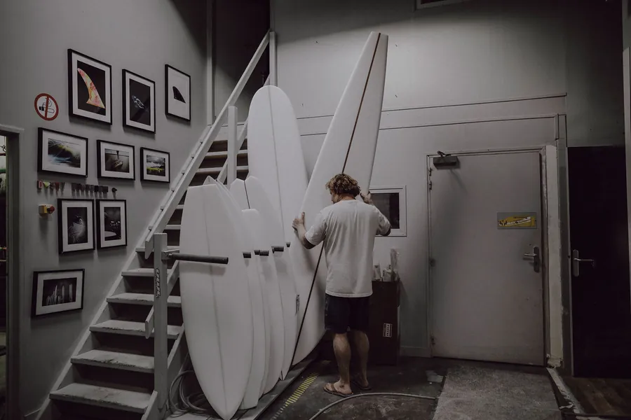 Joshua Martin déplace plusieurs longboards dans l'atelier